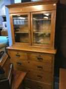 An oak chest of drawers with bookcase top