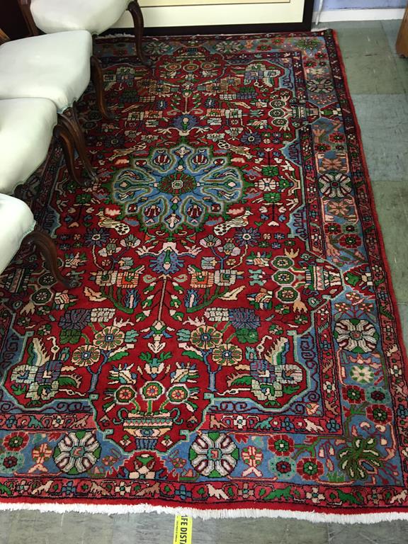 A Persian style rug, the central turquoise pole medallion upon a vibrant red ground, with main