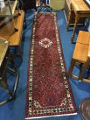 A Persian style runner, the red ground with ivory medallion and all-over geometric design. 293cm x