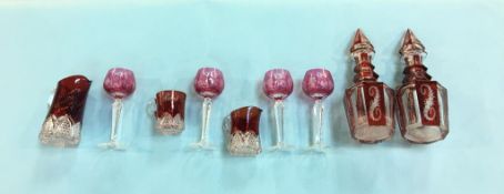 A pair of cranberry coloured decanters, four glasses and three water jugs