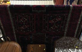 A Baluchi rug, the madder red and midnight blue ground with ivory highlights and geometric motifs.