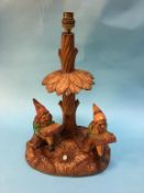 A carved Austrian table lamp, with two gnomes seated under a tree reading, 40cm height.