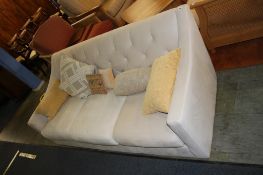 A cream three seater settee (feet to be unpacked)