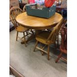 A circular breakfast table and four chairs and another set of four pine chairs