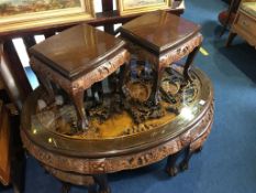 An Oriental carved oval coffee table with six smaller tables