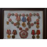 Framed collection of Soviet union medals, badges &