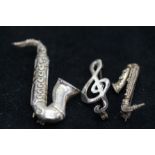 2 possibly silver Saxophones and 1 other pin brooc