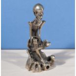 An unusual Chinese silvered metal figure of a Deity sitting on a tree trunk, seal marks to base