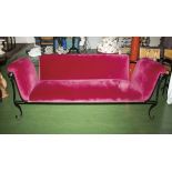 An iron framed couch with red velvet cover.