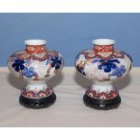 A pair of 19th century squat bulbous imari vases with wood stands