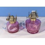 Two cranberry glass oil lamp bases, 16cm and 13cm including the burners