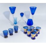 A selection of blue glass wine and shot glasses and a decanter