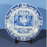 Antique delftware pottery charger with unusual painted decoration, the centre panel depicting a