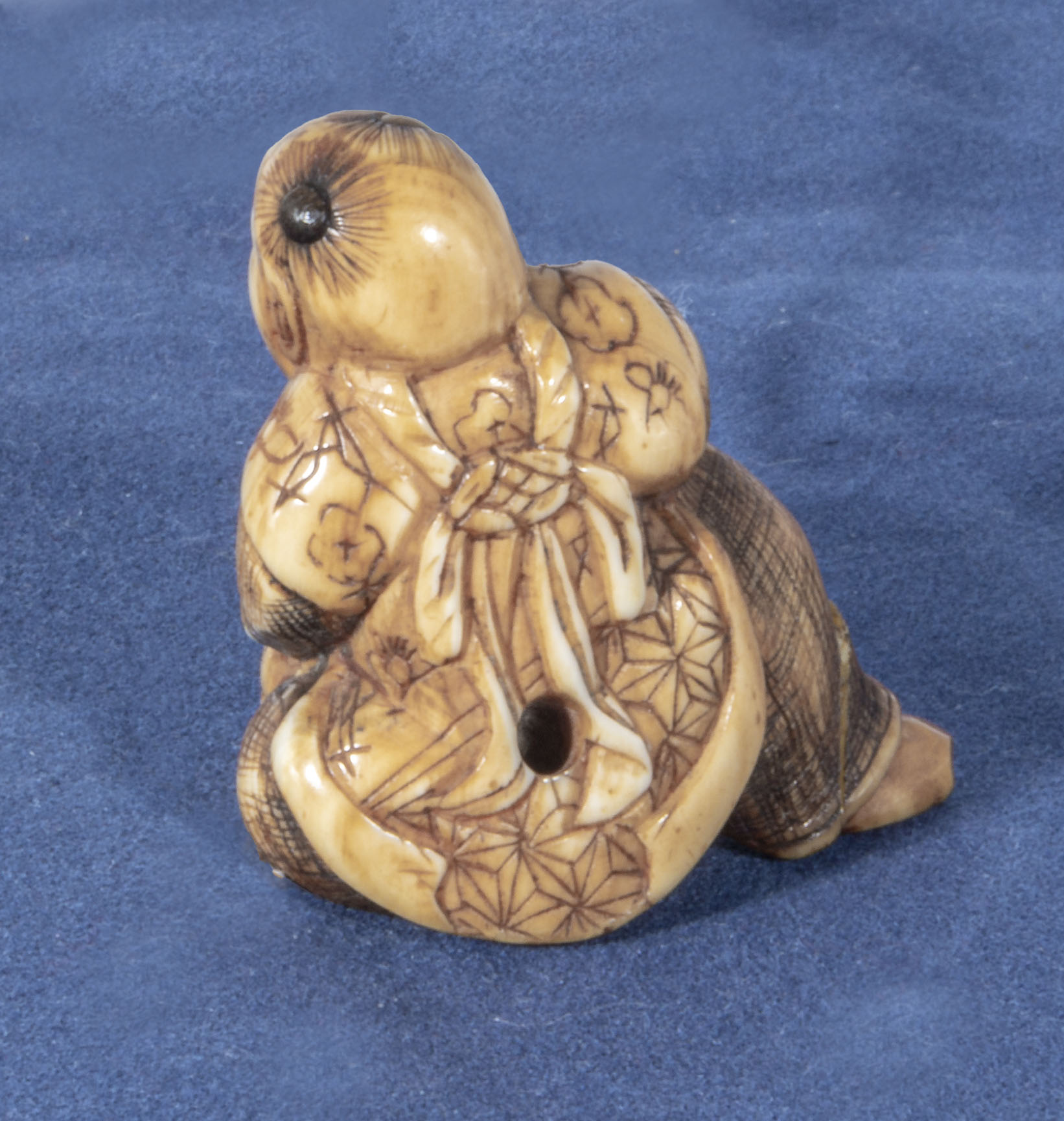 An antique netsuke depicting a man with small horn roundells onlaid on his head carrying a basket, - Image 2 of 3