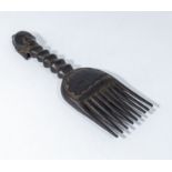 A carved African comb, the handle in the shape of a woman's head with a long neck, 12" in length