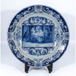 Antique delftware pottery charger with unusual painted decoration, the centre panel depicting a