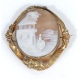 A Victorian carved oval shell cameo depicting a lady in a village setting with houses, in a gilt