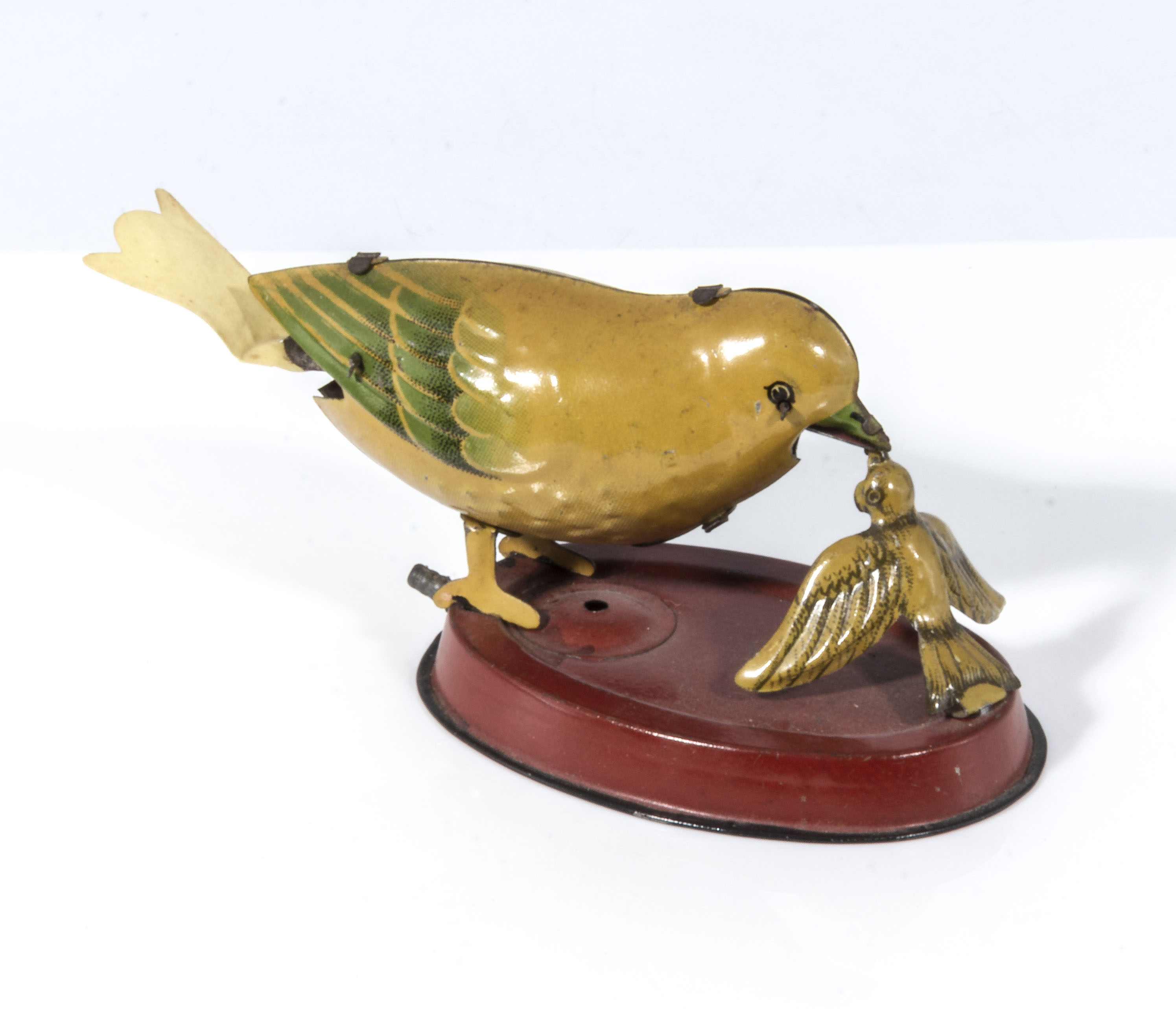 A vintage tin toy of a bird feeding her chick, base measures 7cm, the bird measures 10cm