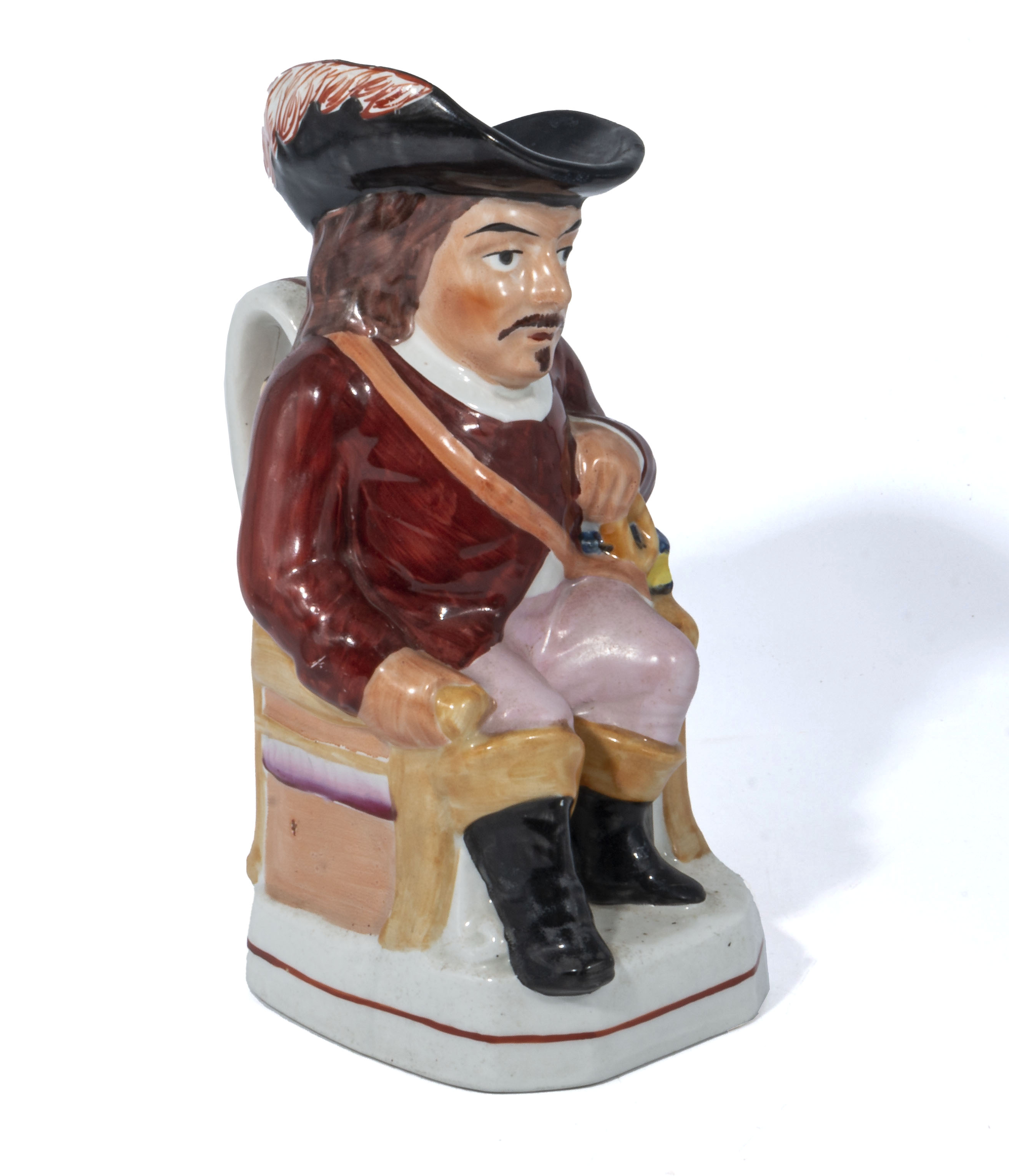 An antique Staffordshire Toby jug, in the form of a seated cavalier wearing a red coat and holding a