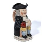 An antique Staffordshire Toby Philpot, wearing a black coat and hat holding a jug of ale, 9" high