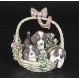 A Lladro figure group of a basket of puppies, 6" tall and 5" dia.