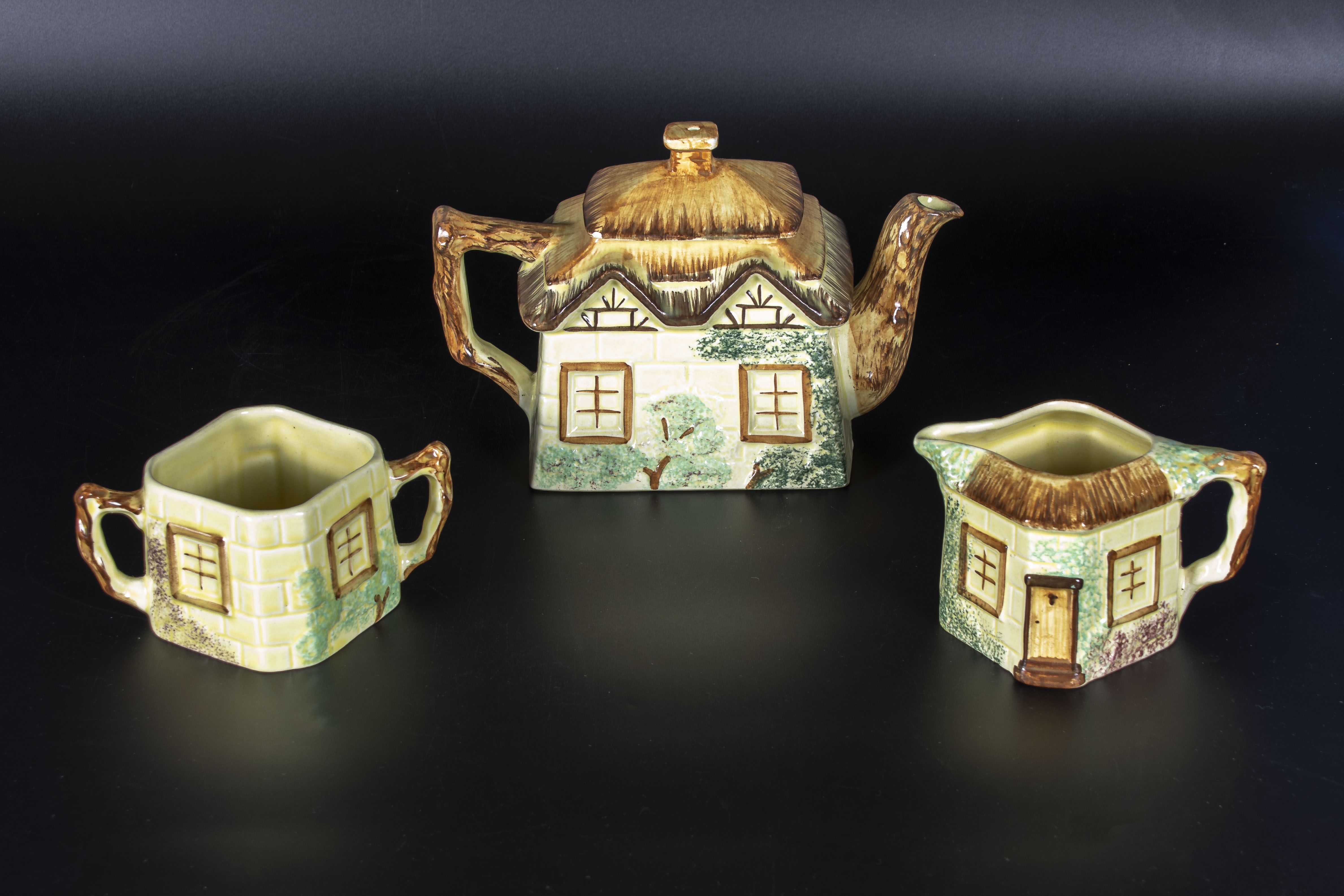 A cottage ware teapot, sugar and cream