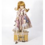 Automated musical box clock-work doll on a wooden base, the doll has a porcelain head and hands,