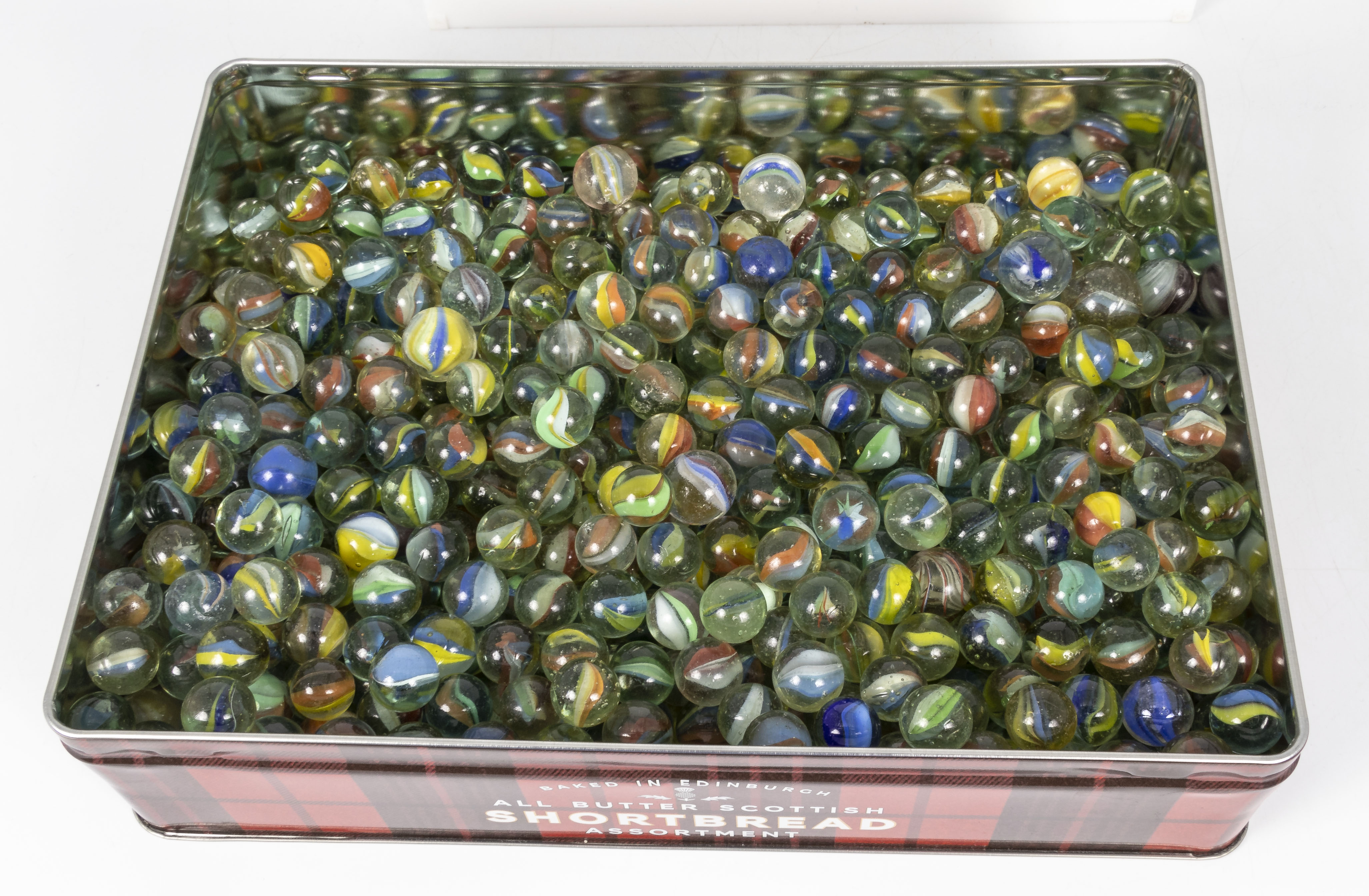 A tin box full of hundreds of vintage glass tri-coloured marbles