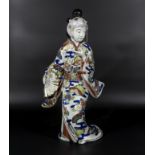 Japanese antique porcelain figure of a Bijin, wearing a decorative swirling dress and holding a