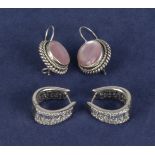 A pair of silver earrings set with a pink stone and a pair of silver horseshoe shaped earrings