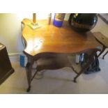 A late Victorian/early Edwardian two tier occasional table with split hoot feet, carved mythical