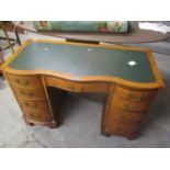A reproduction walnut serpentine fronted twin pedestal desk having a green leather topped scriber