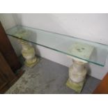 An architectural design table having a glass top and two stoneware pedestals 29 1/2"h x 65"w