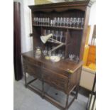 An early 20th century oak dresser having a plate rack above drawers and cupboards 75"h x 49 1/2"w