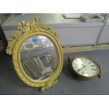 A painted wooden framed oval wall mirror with strut back and an oak cased dial clock with rope twist