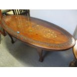 A modern Indian oval topped coffee table having brass inlay, 18 1/4"h x 55"w