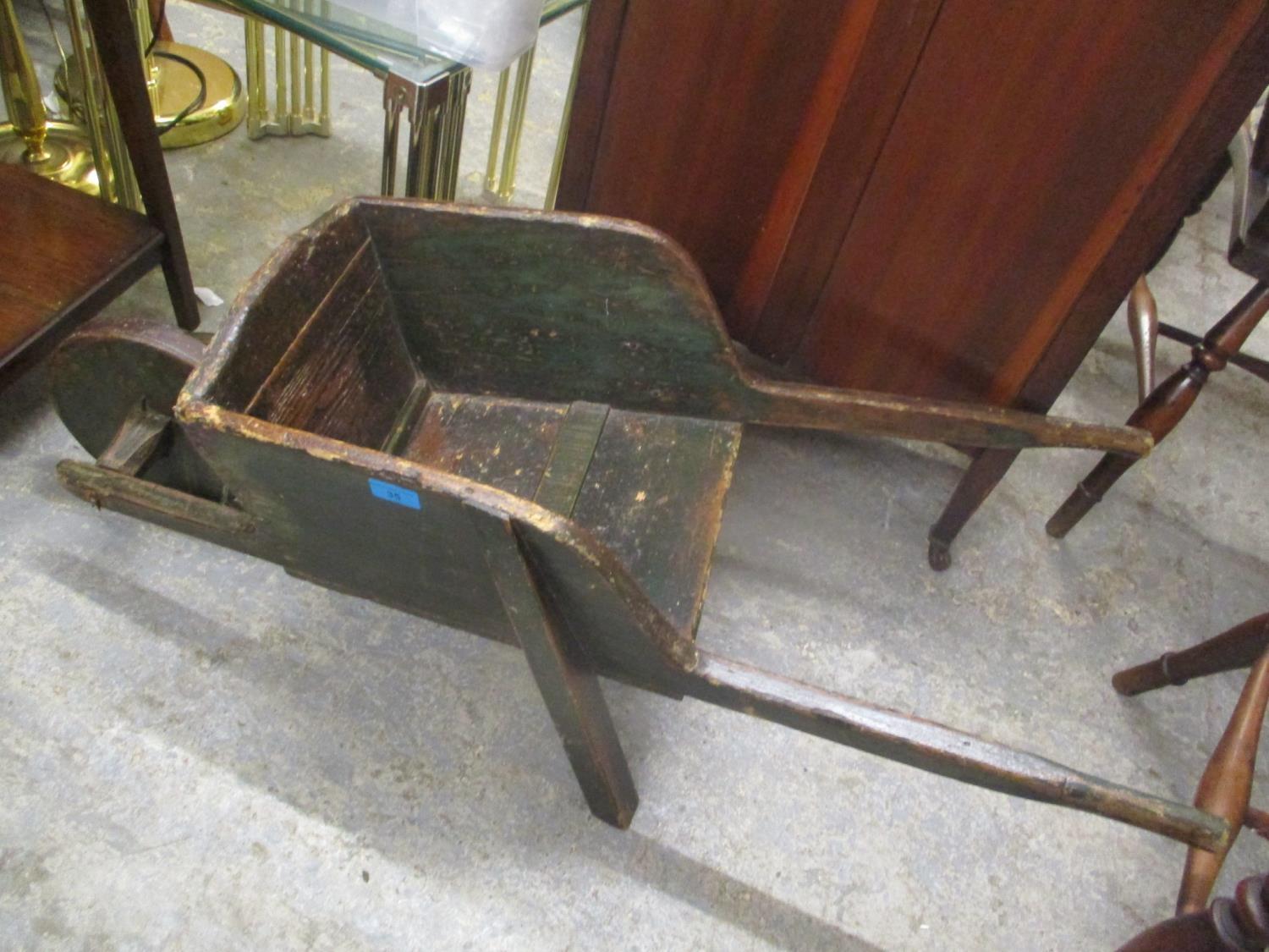 An early 20th century green painted and polished pine child's wheelbarrow