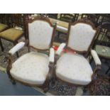 A pair of late Victorian carved walnut armchairs with upholstered backs and seats, on turned legs
