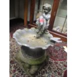 A garden ornament of girl on a bird bath, possibly lead, on a stoneware base