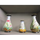 Three Victorian painted ceramic vases with black base and rims, the body of the vases painted with