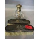 Two silver backed hair brushes and a silver topped bottle