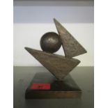 A contemporary bronze abstract sculpture, a circular sphere between two elongated triangles, on a