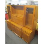 An Ercol blonde elm, three section bookcase cabinet having glazed doors flanking a fall flap above