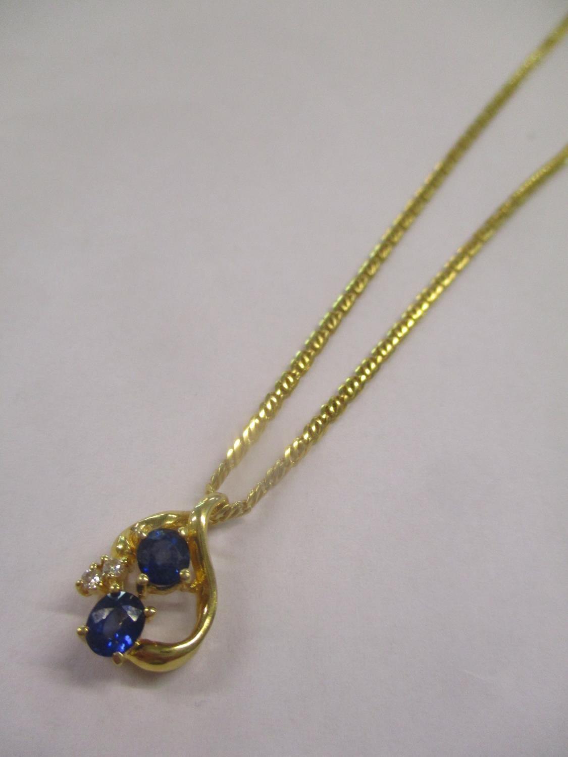 A gold coloured metal necklace and pendant set with diamonds and sapphires