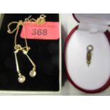 An Edwardian yellow metal set bow pendant with two pendant drops set with white stones and split