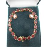 A yellow gold coloured metal bracelet set with garnets, stamped 10ct and two similar earrings,