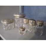 A selection of silver topped dressing table jars to include a Victorian jar having a floral embossed