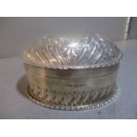 A late 19th/early 20th century silver embossed oval box with lid