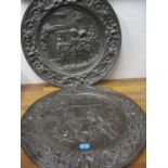 A pair of patinated brass pressed chargers embossed with figures