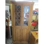 A large modern pine corner display cabinet having glazed doors above two cupboard doors, 75 3/4"h